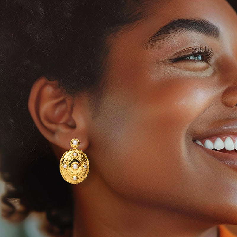 Gold drop earrings with white pearl centers and small top pearls on model ear