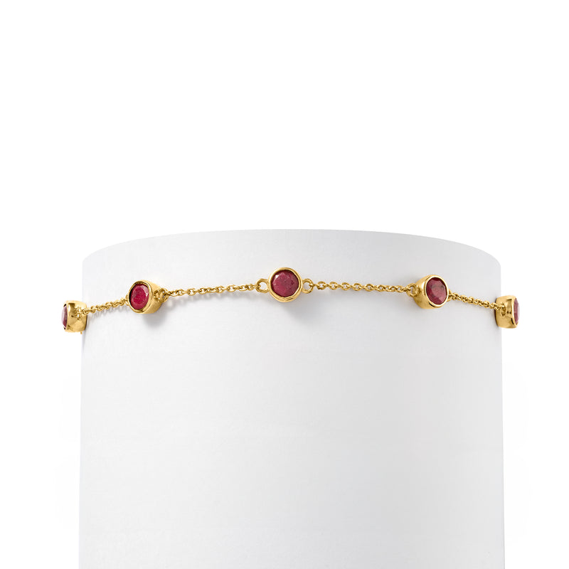 Slim gold bracelet with round bezel-set ruby stations and bar clasp