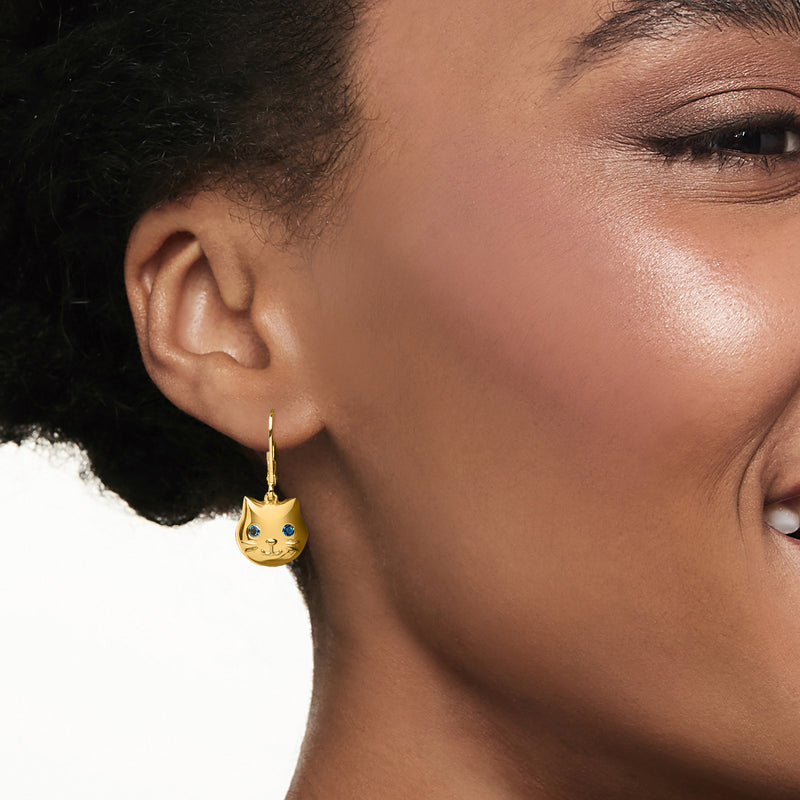 Gold cat drop earrings with blue gem eyes worn on ear, leverback style