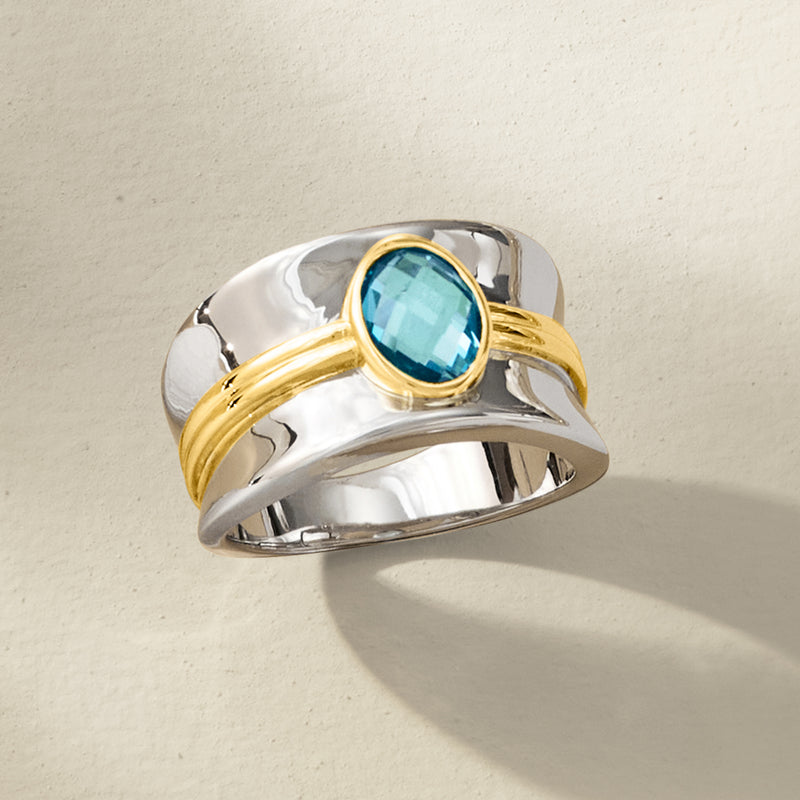 Polished two-tone ring with oval blue topaz and gold wrap around center