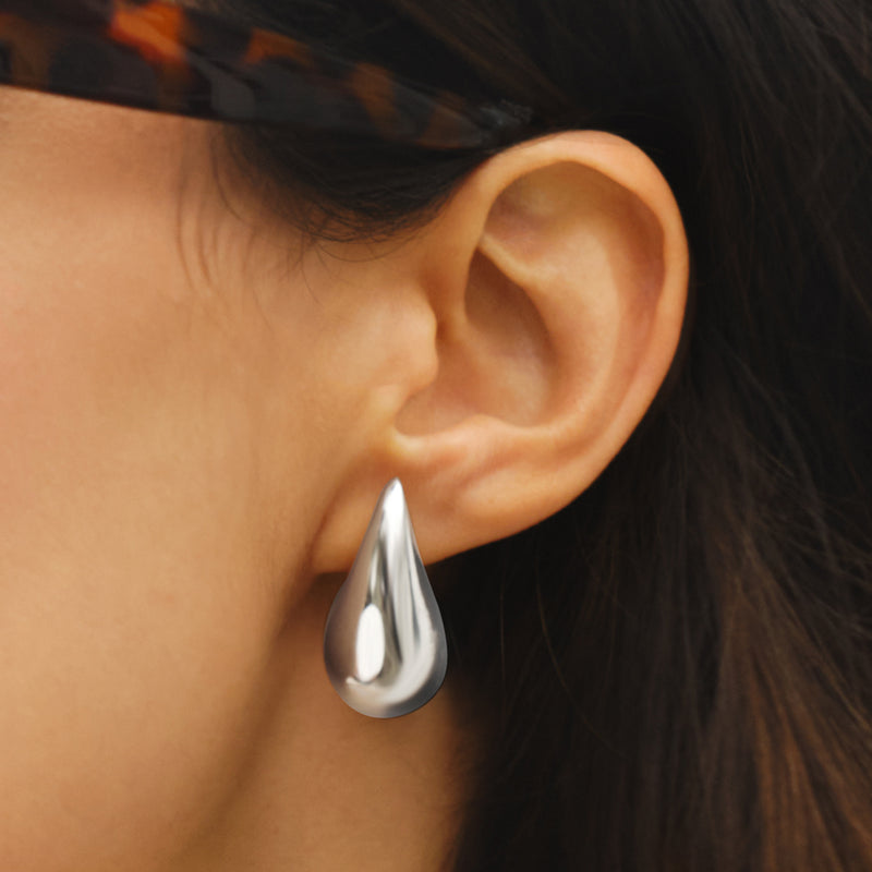 Sterling silver teardrop drop earring on ear, reflective teardrop pendant