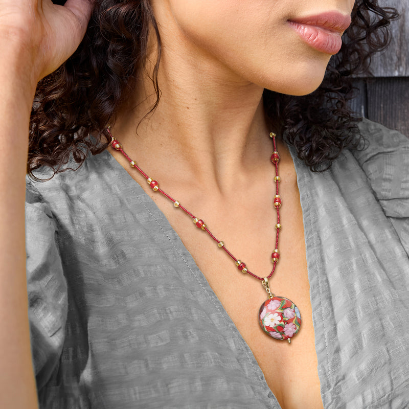 Floral glass disc pendant necklace on model, red bead strand with gold-toned chain
