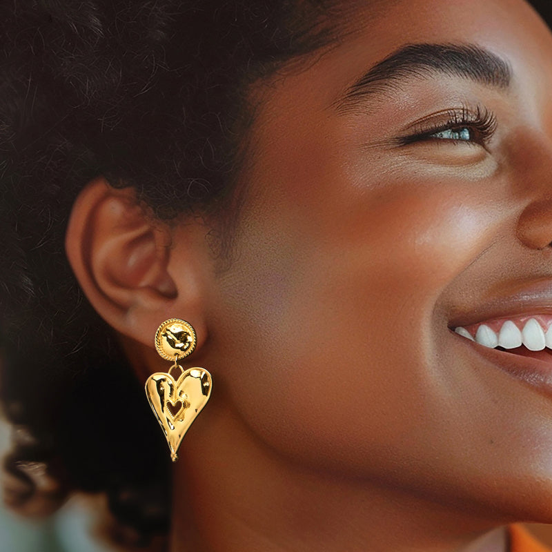 Gold heart drop earrings on model, scalloped round studs with dangling asymmetrical heart