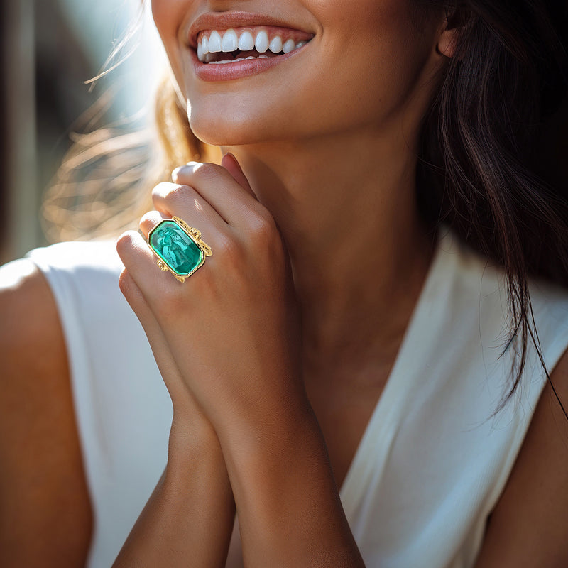 Gold-tone angel ring with turquoise octagon glass worn on a finger