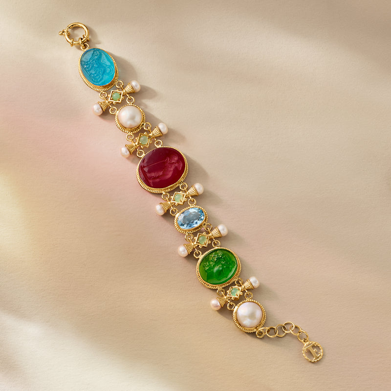 Gold-tone bracelet laid flat with colorful oval glass gems and white pearl accents