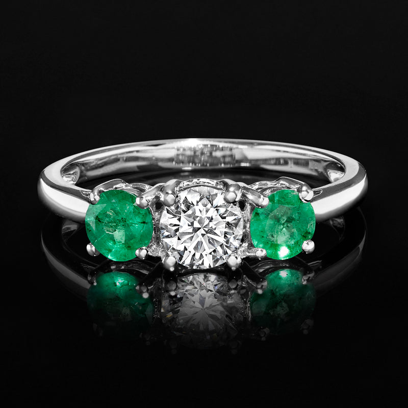 14kt white gold ring with round diamond centerpiece and two emerald side stones