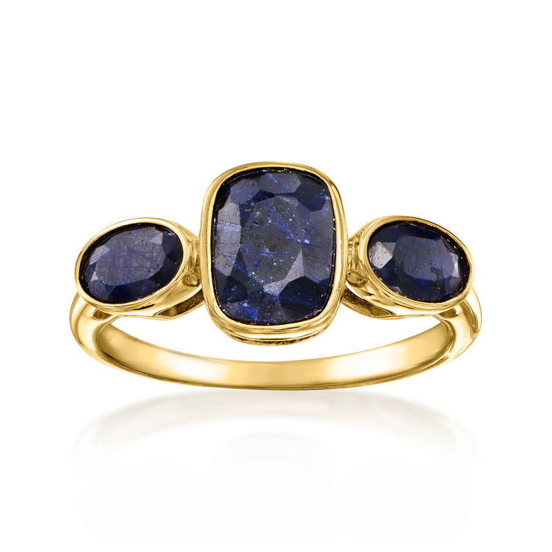 Gold three-stone ring with cushion-cut blue sapphires on a smooth band