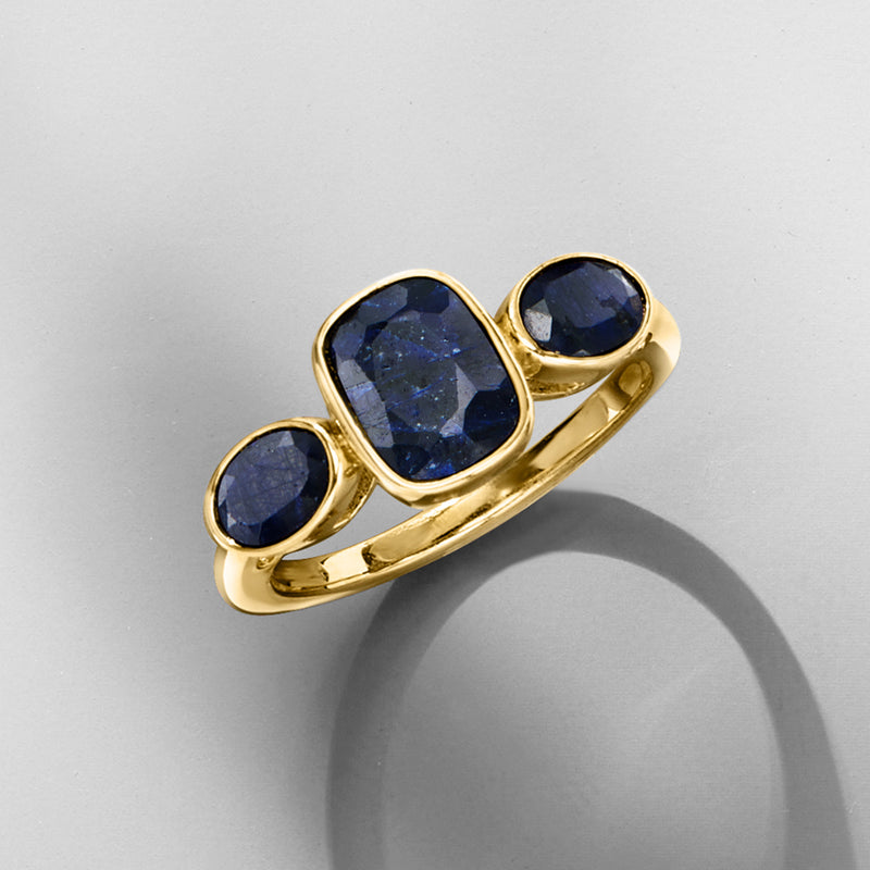 Gold three-stone sapphire ring with three dark blue round stones on a curved band