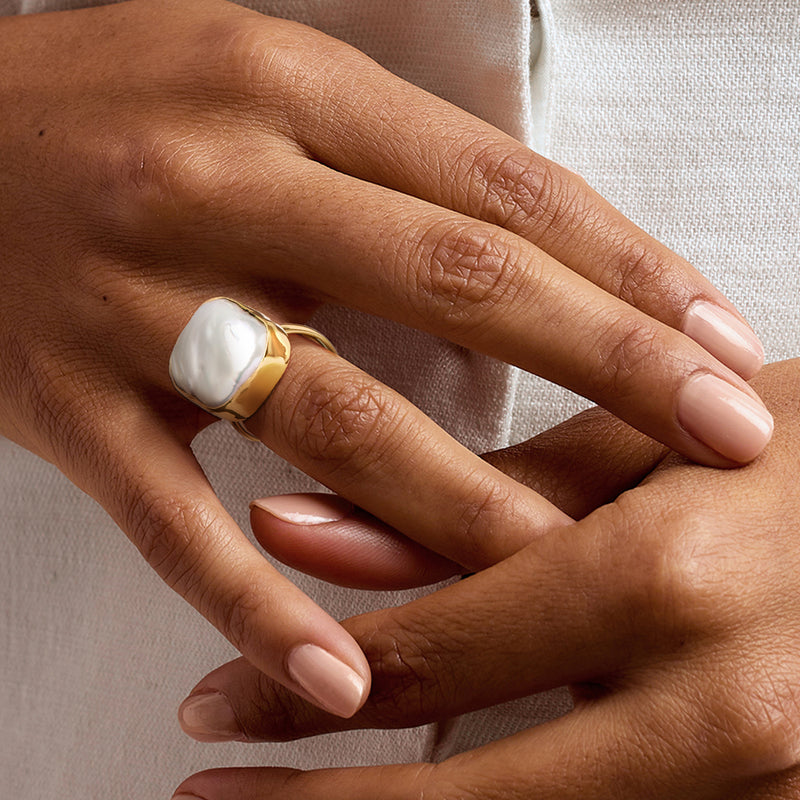Cultured baroque pearl ring on hand, oval white pearl in gold over sterling setting