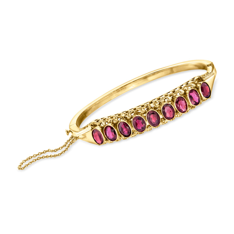14kt yellow gold bangle bracelet with oval pink garnet stones and dangling safety chain