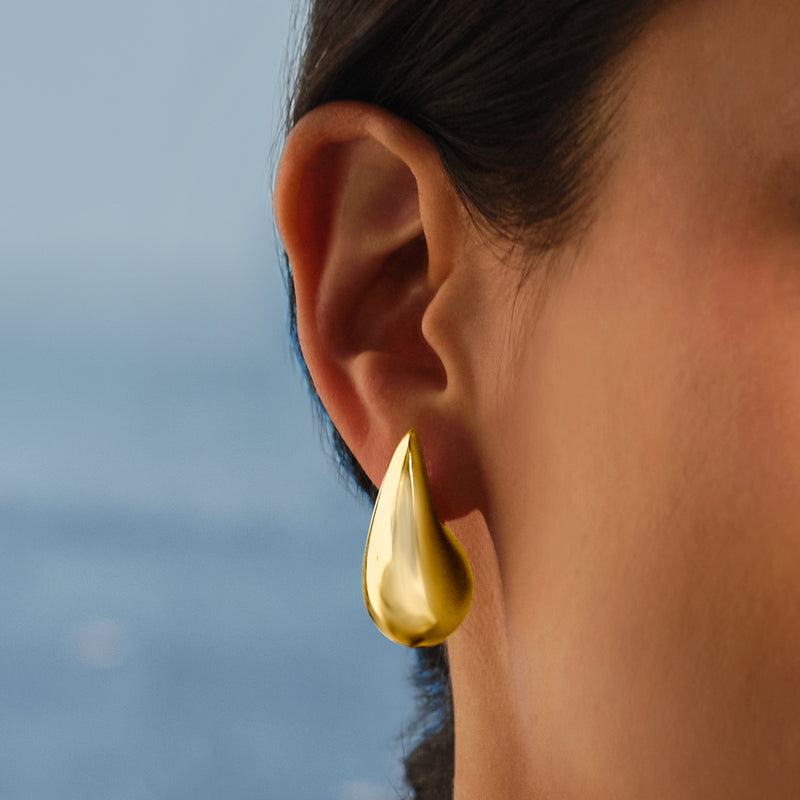 Gold teardrop drop earring on ear with polished teardrop silhouette