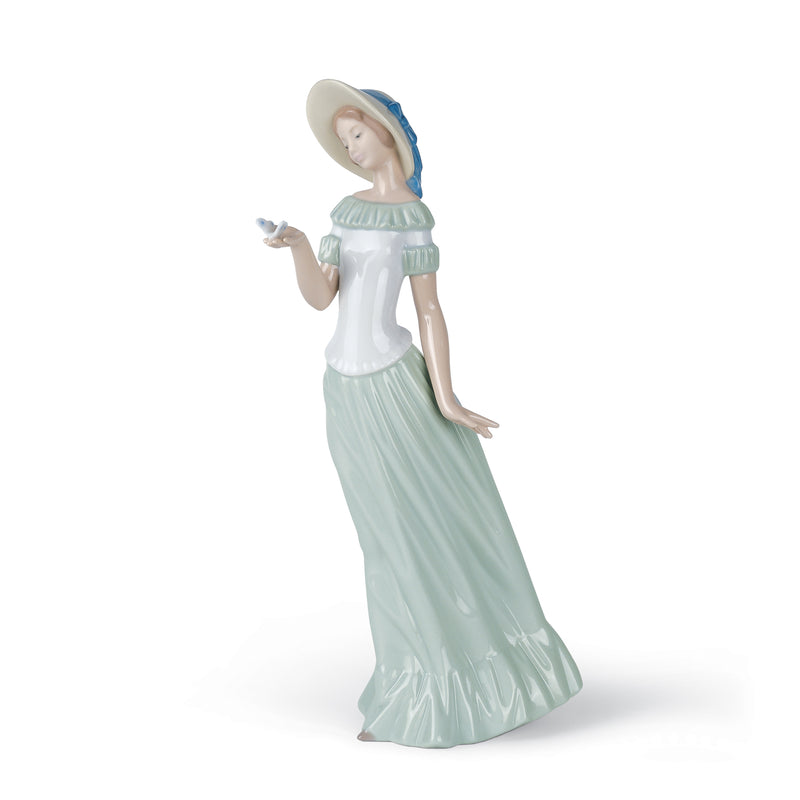 Porcelain figurine of a standing woman in a light green gown and blue bonnet, hands raised