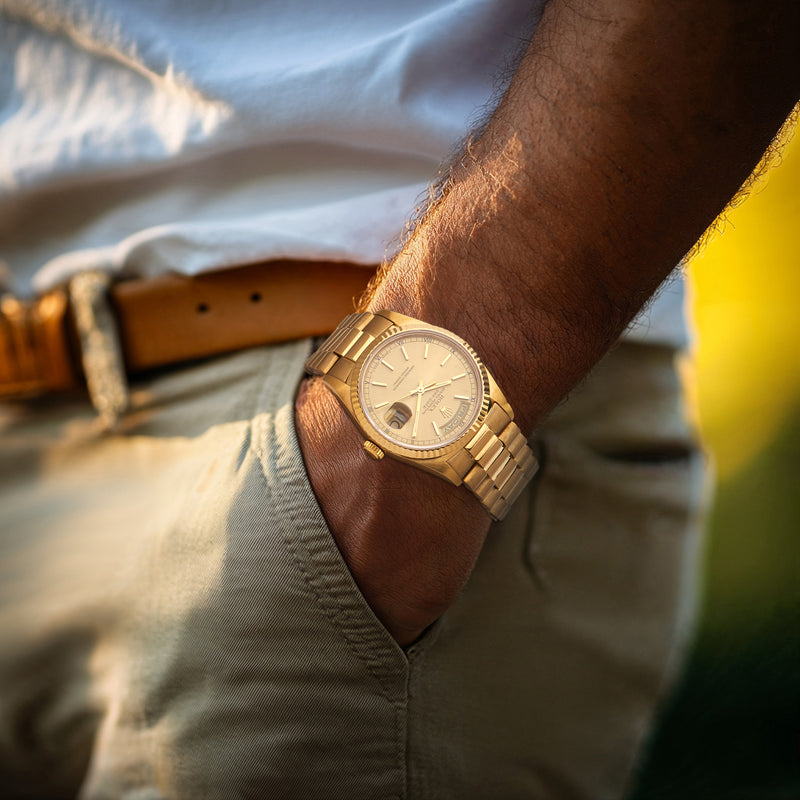 Rolex Day-Date men's yellow gold watch on wrist with gold metal bracelet