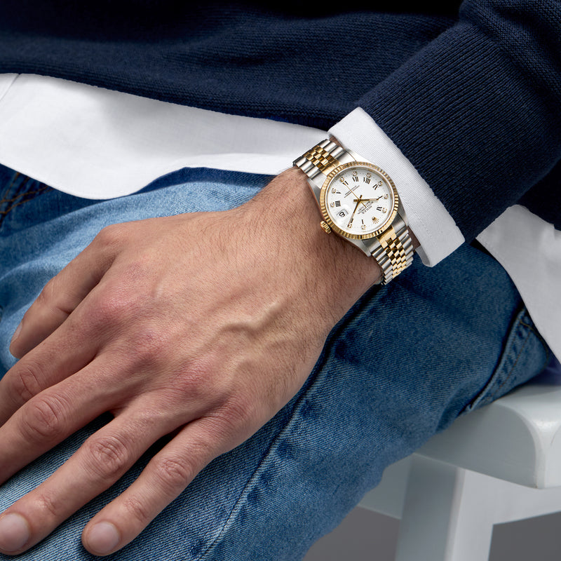 Two-tone gold and steel watch on wrist, white dial with date window