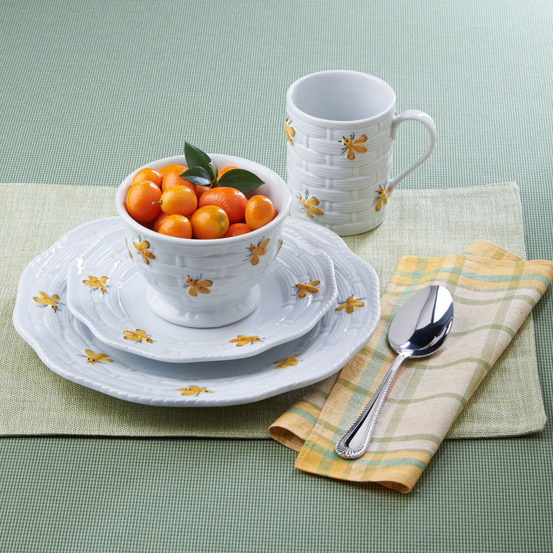 White ceramic dinnerware set with bee motif, bowls, plate, and mug