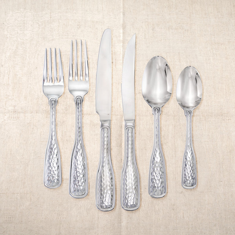Stainless steel flatware with hammered handles, including forks, knives, and spoons