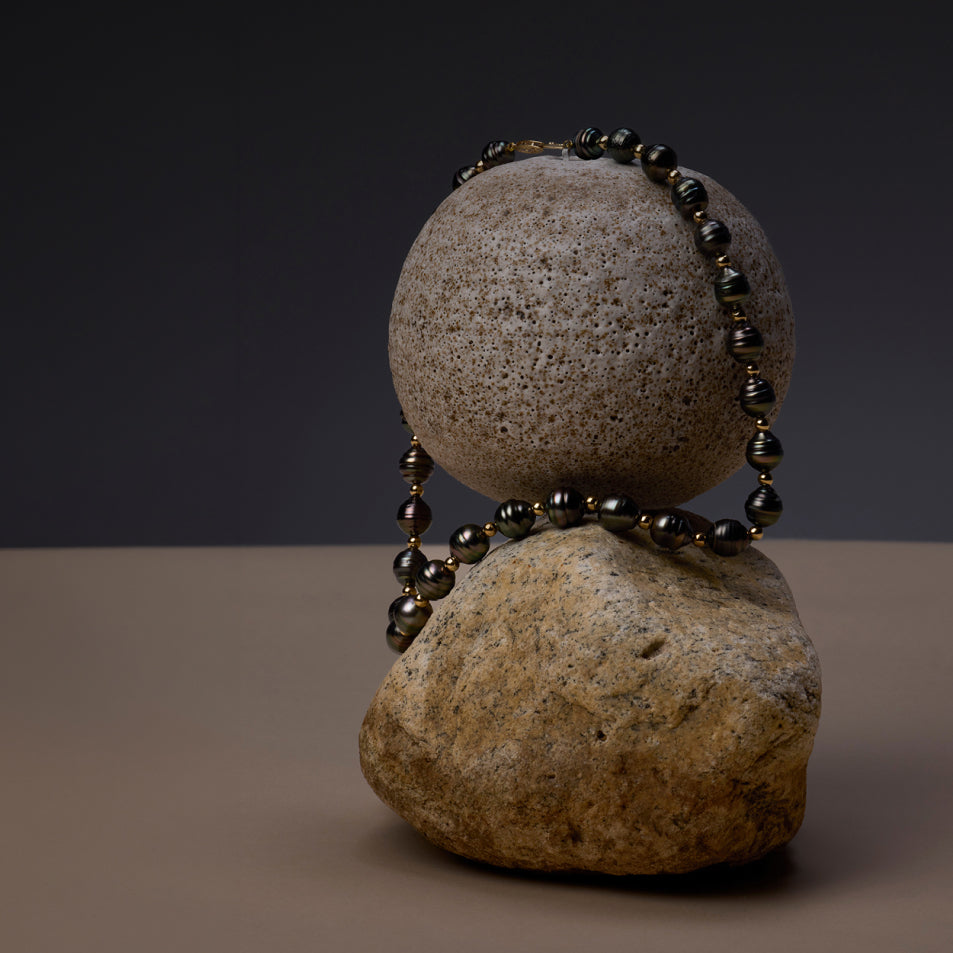 Pearl necklace laid atop two stones