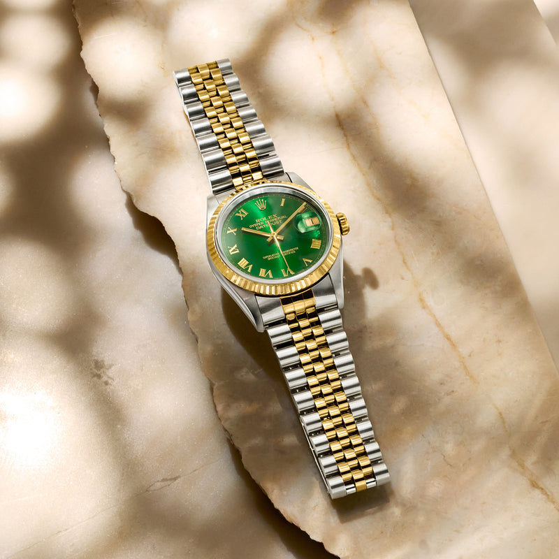 Two-tone stainless and yellow gold watch with green dial and gold Roman numerals on bracelet