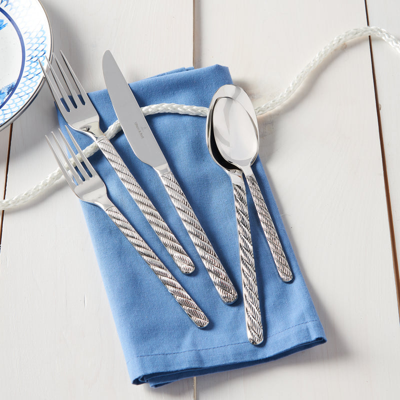 Stainless steel flatware set with fork, knife, and spoon on blue napkin