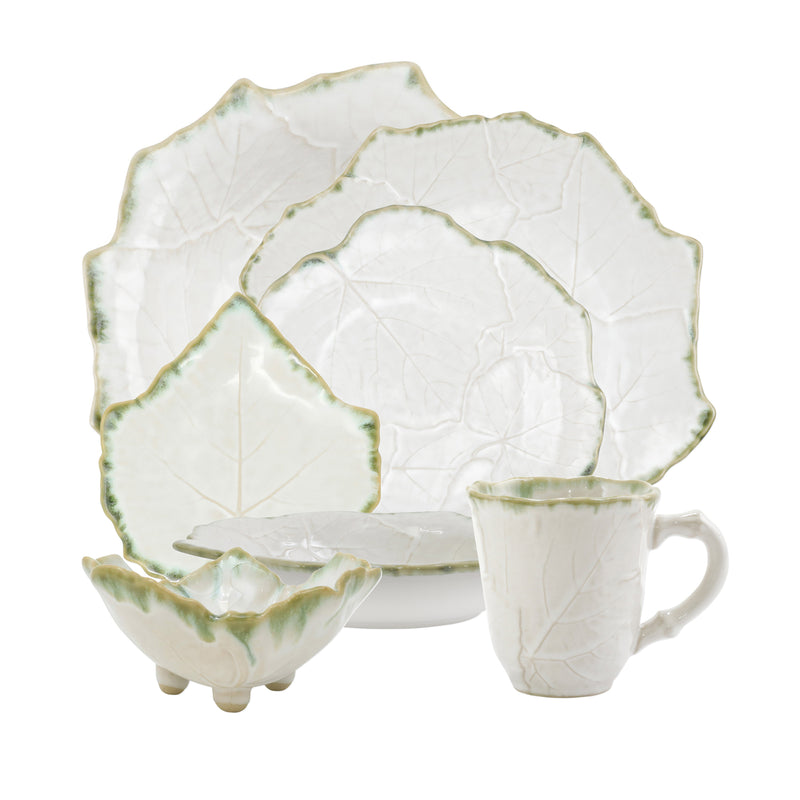 White dinnerware set with green leaf pattern, scalloped rims, and matching cup