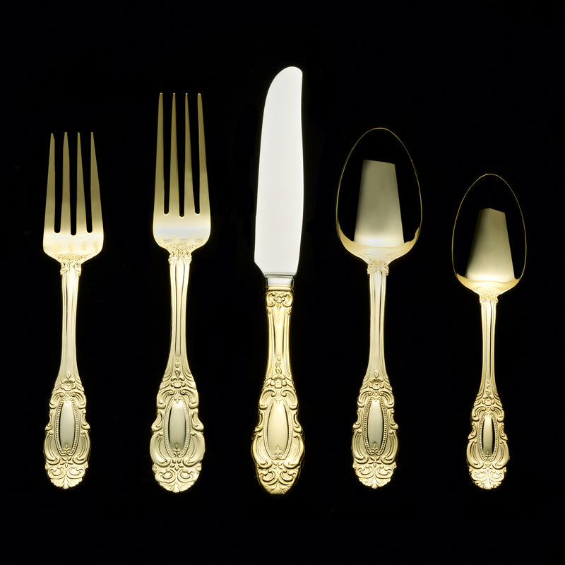 Gold-tone flatware set with ornate forks and spoon, polished finish