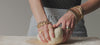 Close up of video including women's hands kneading dough while wearing gold bracelets and rings