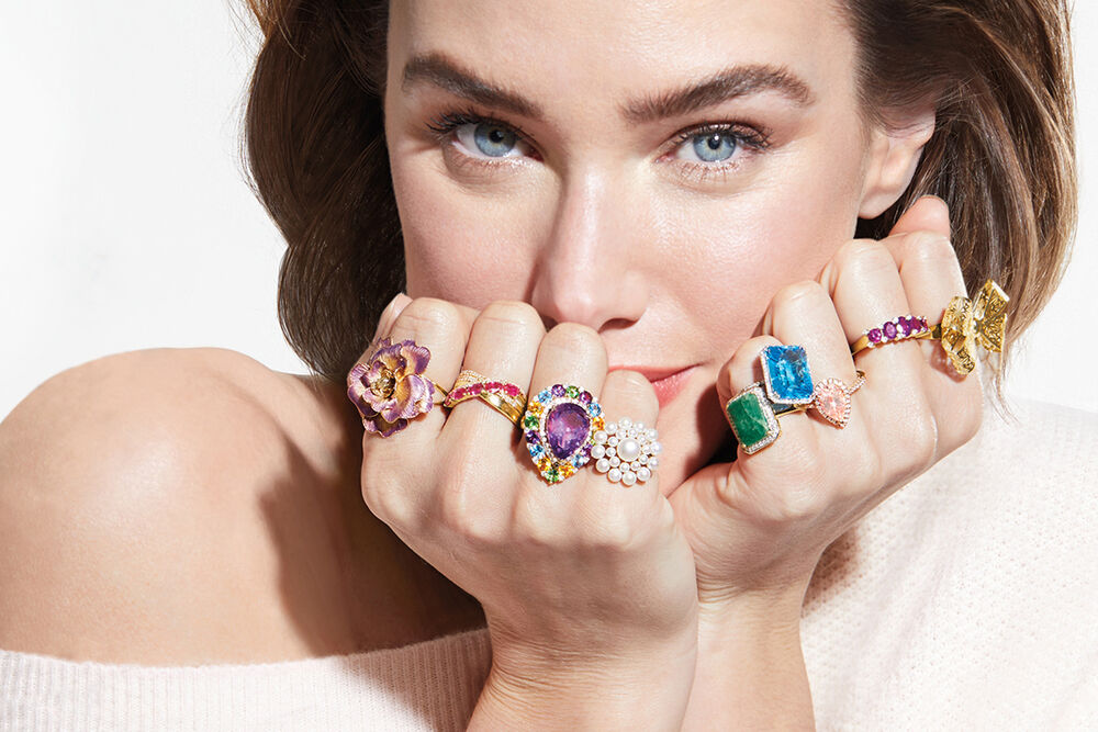 Model wearing different gemstone rings on every finger.