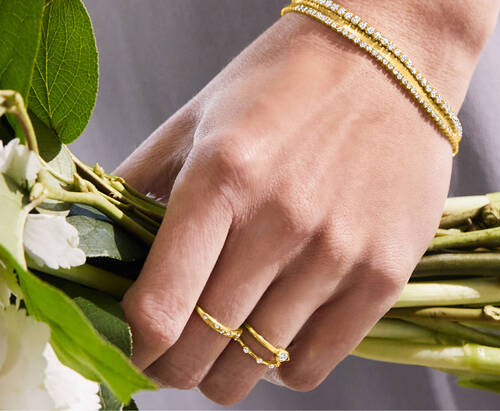 image featuring a Hand Holding Flowers Wearing Gold Rings and Bracelets