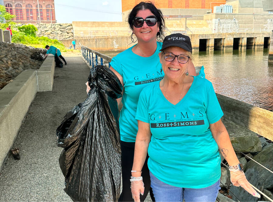 Two call center employees volunteering cleaning up the river front in downtown Providence