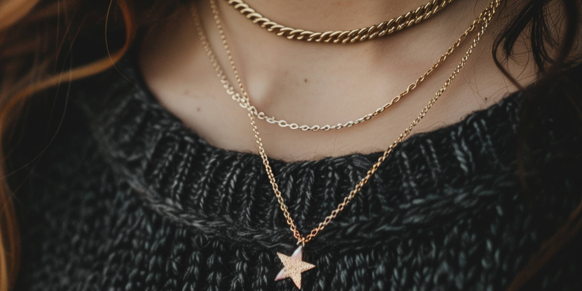 three layered necklaces atop person wearing sweater 