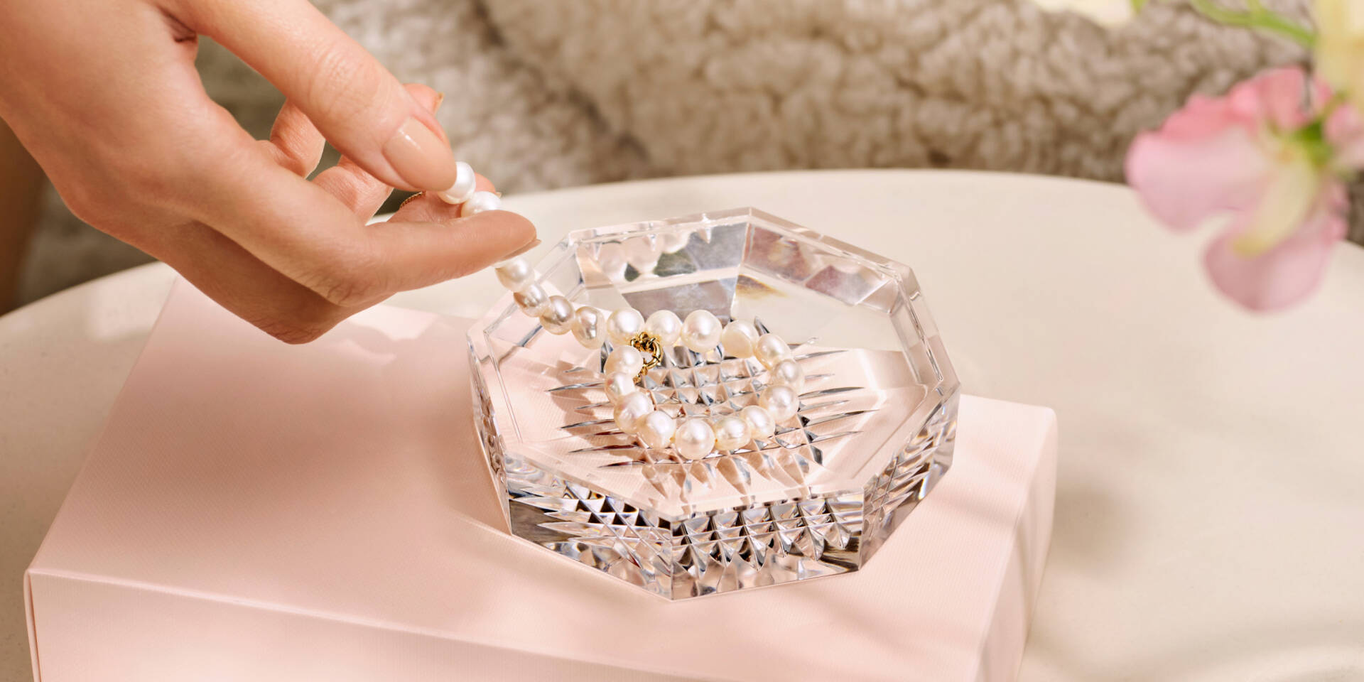 glass tray with pearl bracelet and hand 